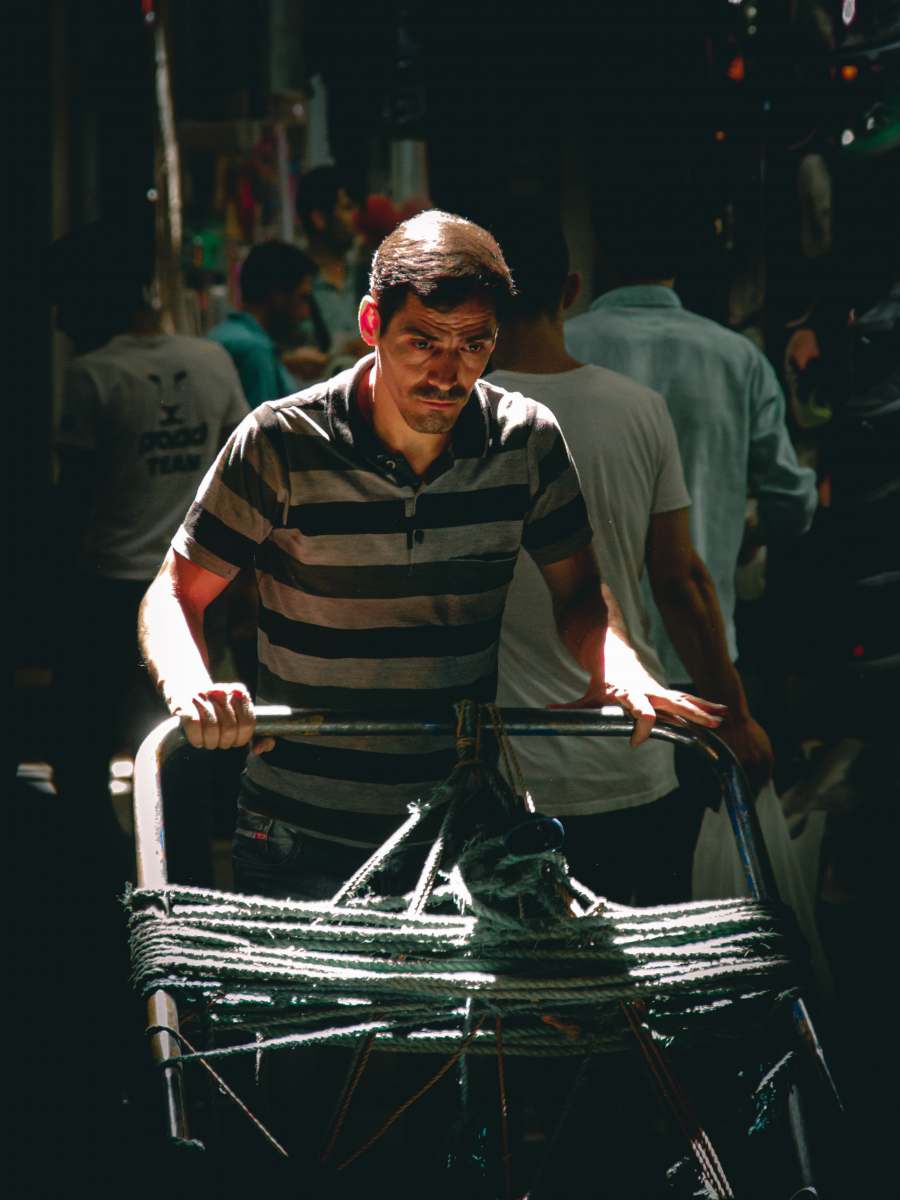 tehran man in black and white stripe polo shirt holding black plastic bag iran